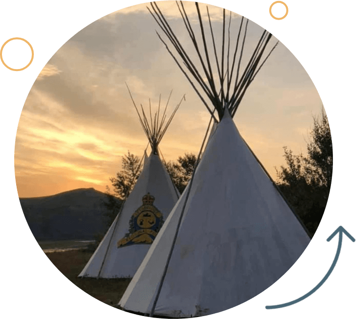 A group of three white teepees in front of the sun setting.